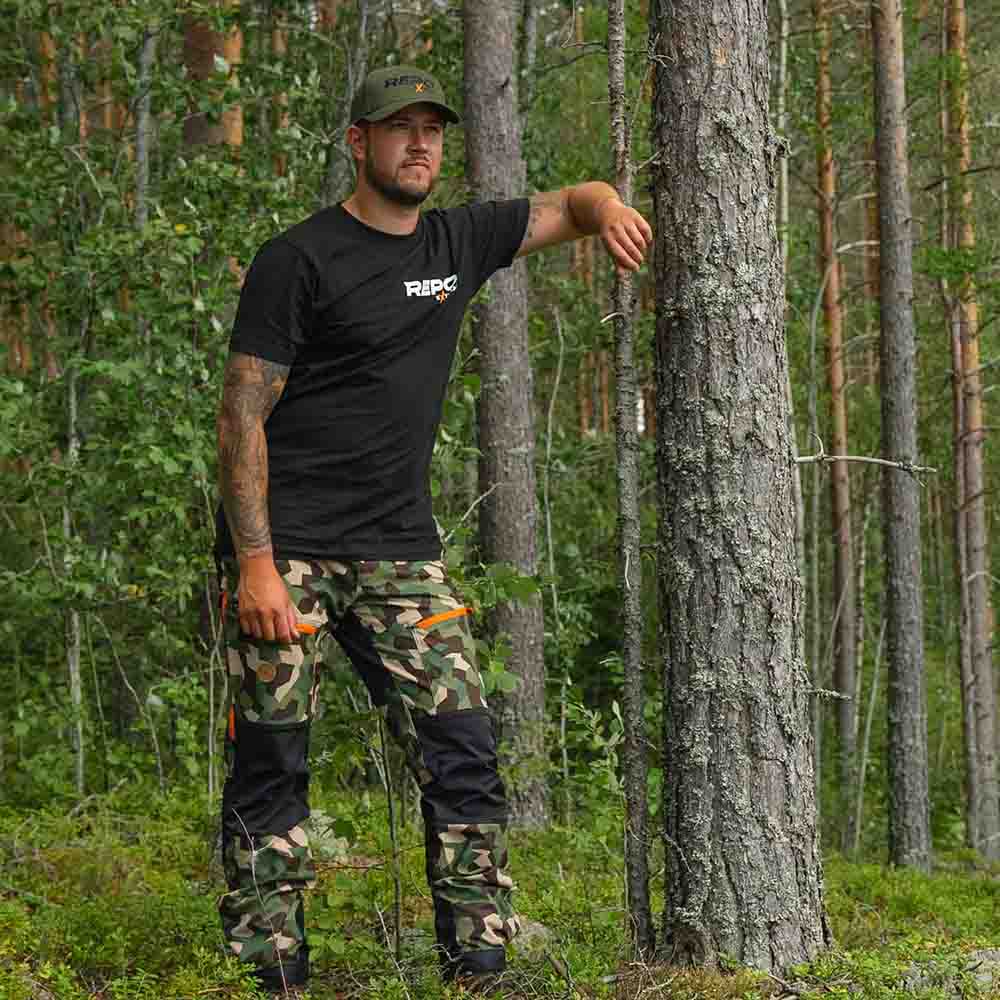 Nokko Camo ulkoiluhousut miehille mallin päällä metsässä