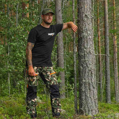 Nokko Camo ulkoiluhousut miehille mallin päällä metsässä