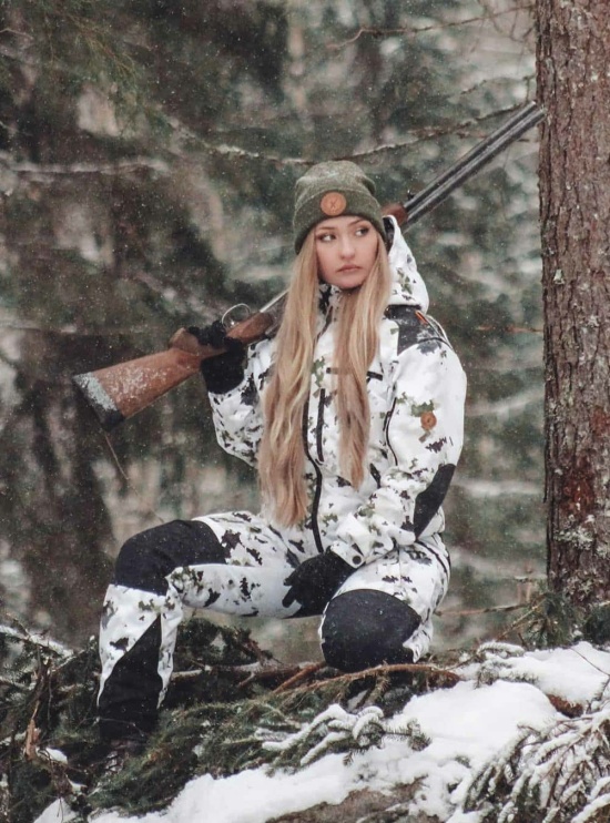 Naruska lumicamo metsästyspuku naisen päällä metsällä